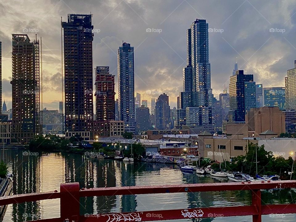The views from the „Pulaski Bridge“ at „Newtown Creek“ in LIC are truly spectacular. In the water of the „East River“ there is a variety of boats and straight ahead we see a combined skyline of „Queens“ and of „Manhattan“. 2023. Hypnotic Productions