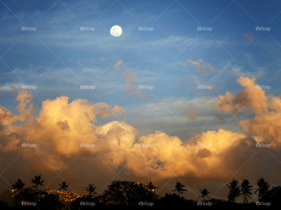 Full moon over a Honolulu landscape at sunset