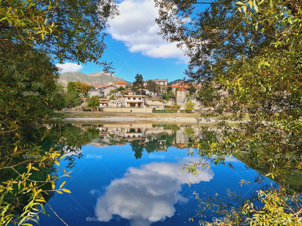the town of Villalago is reflected in the calm lake