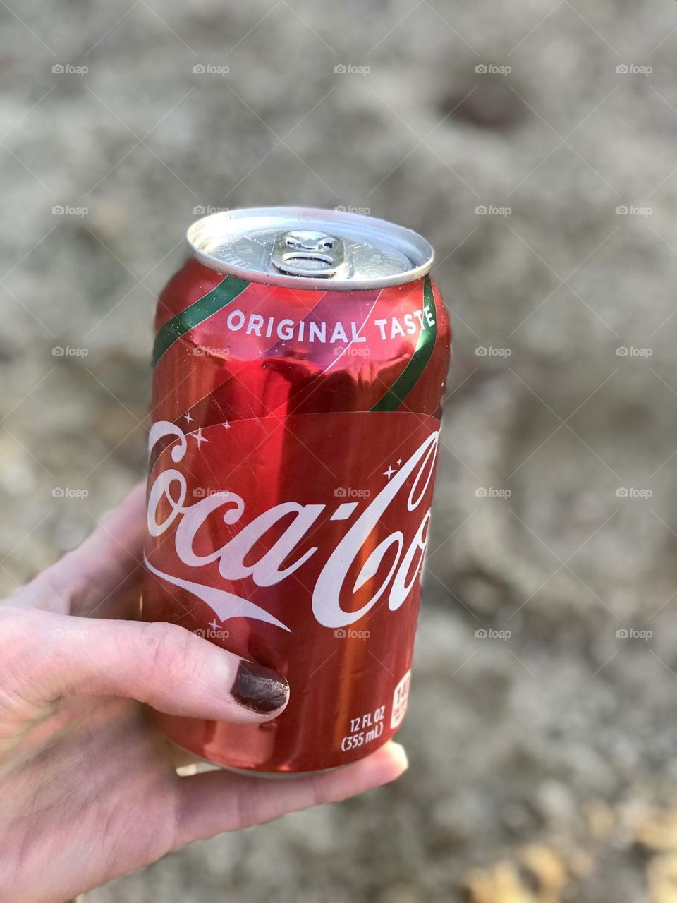Holding a coke can by the sand 