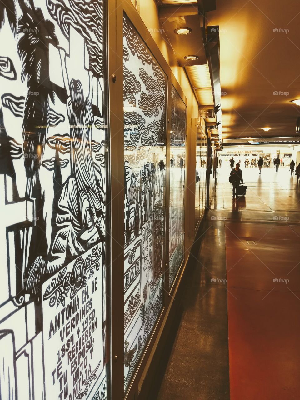 A mural reflects light while travelers move through the Los Angeles transit station.