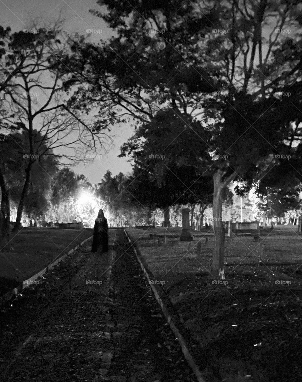 Cloaked figure in graveyard at night, spooky 