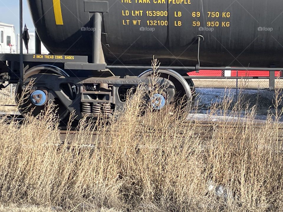 A black gas tank train passing by and I love how the wild grasses grow along the tracks, this was taken on a calm winter day but no snow, means its a great day here in Alberta, Canada!