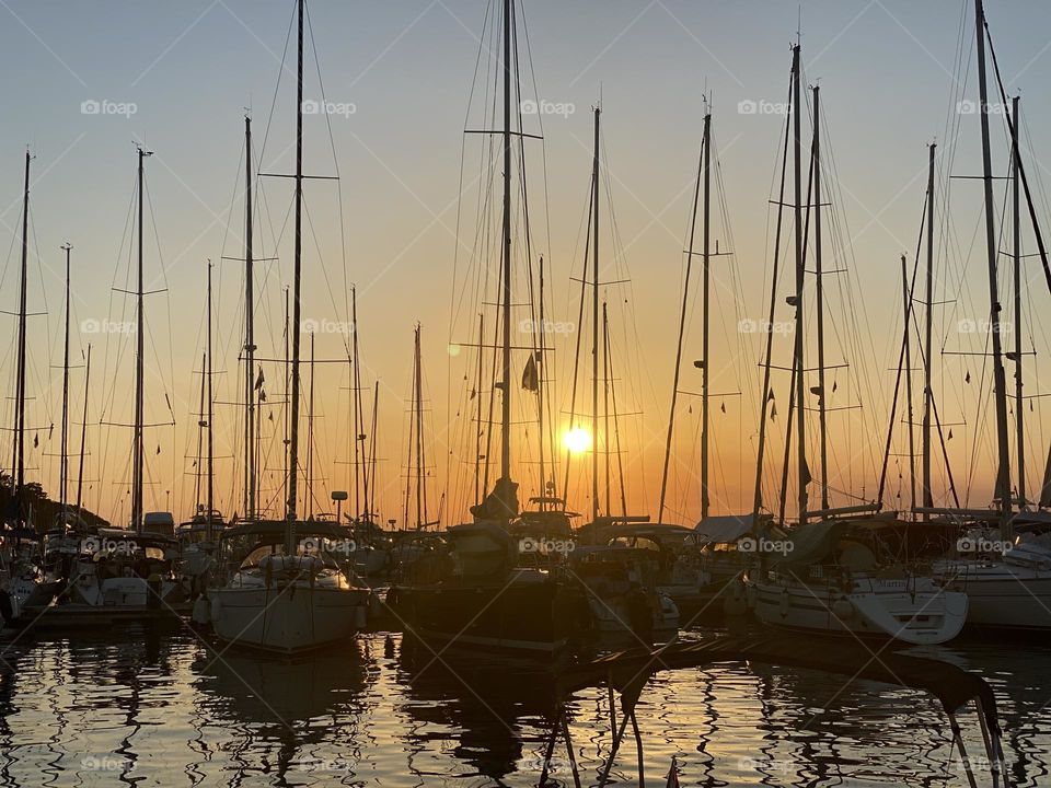 beautiful red summer sunset on the pier against the background of boats, yachts, ships