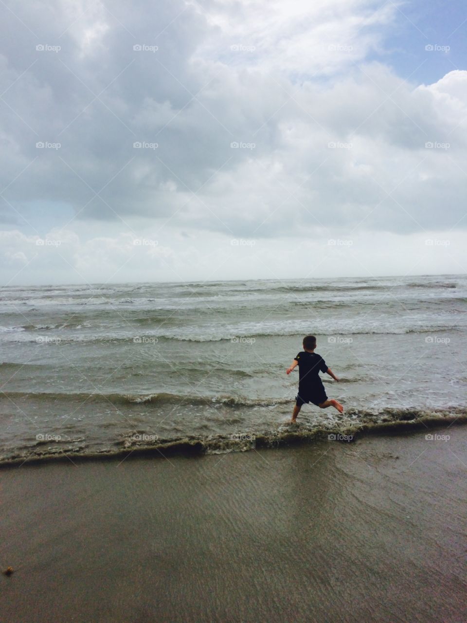Happy child running on the beach at the ocean. 