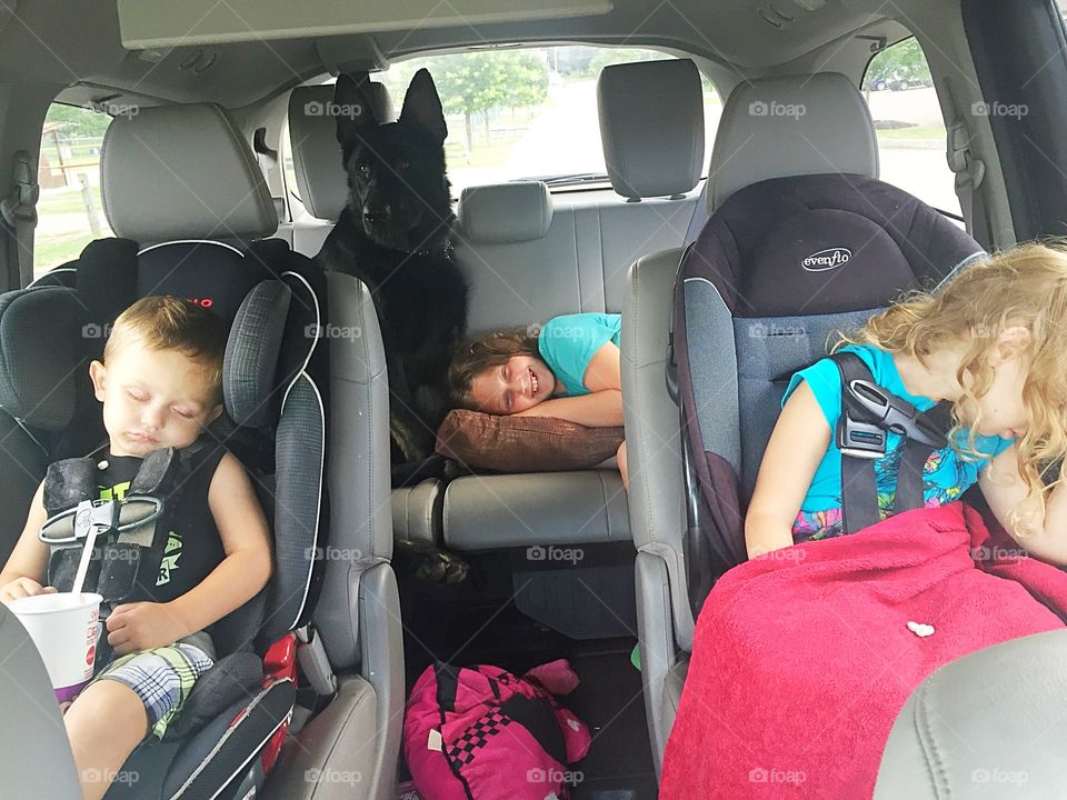 Brother and sisters resting in car with dog