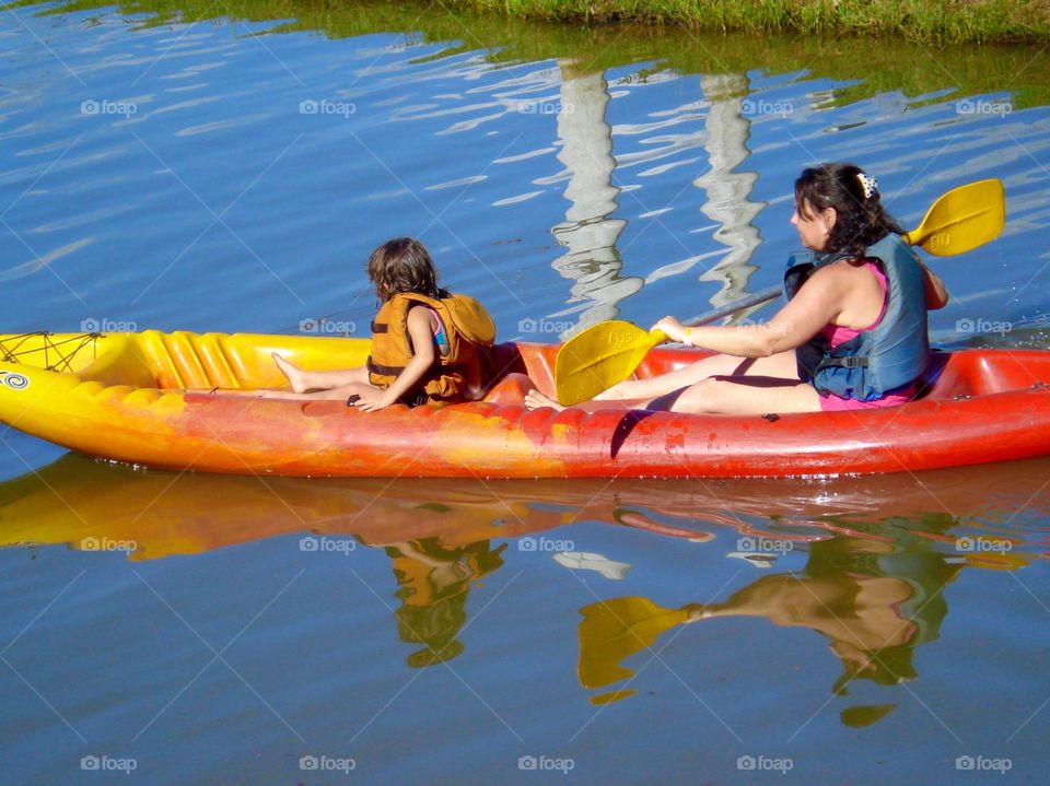 Leisure time - mother and daughter kayaking on the lake during summer vacation