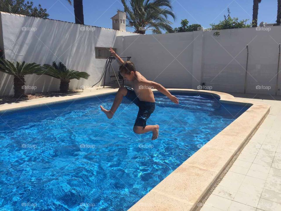 A boy jumping in a swimming pool, summer, Spain