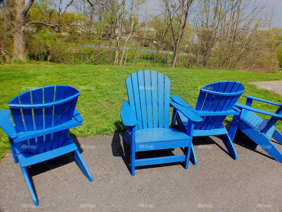 bright bluelawn chairs sitting out by the green grass for people to sit and rest