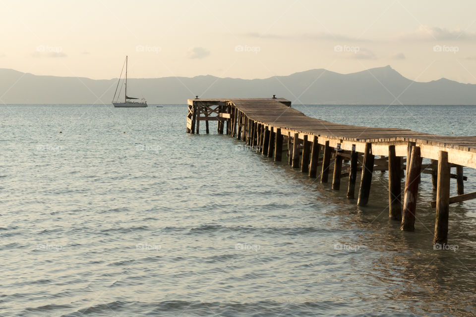 Wooden pier in the ocean at sunrise 