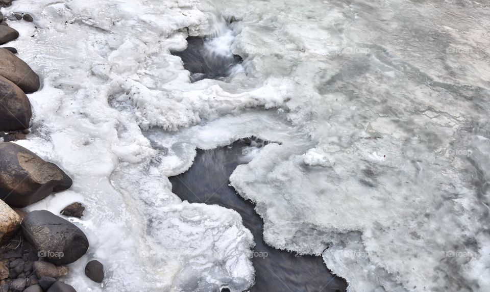 An aerial view of a rather striking and simple mountain creek covered in thick slabs of ice.