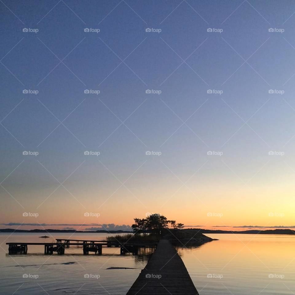 Scenic view of small island and pier in sunset