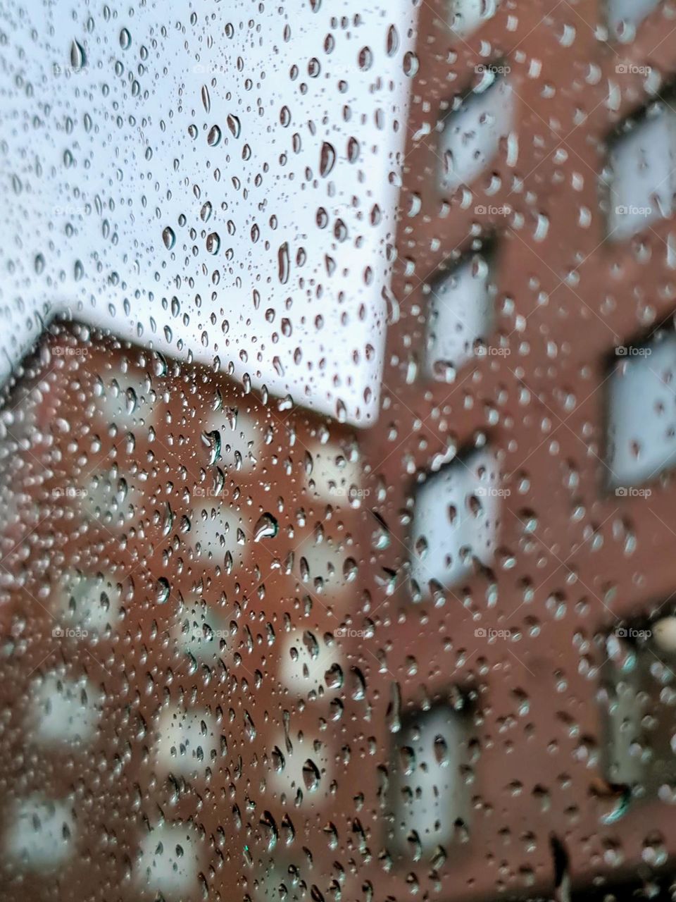 Rainy day city view through the wet glass with the water drops