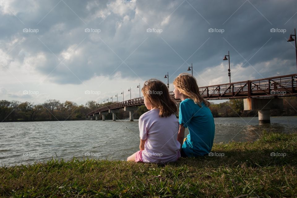 Two girls sitting by a lake