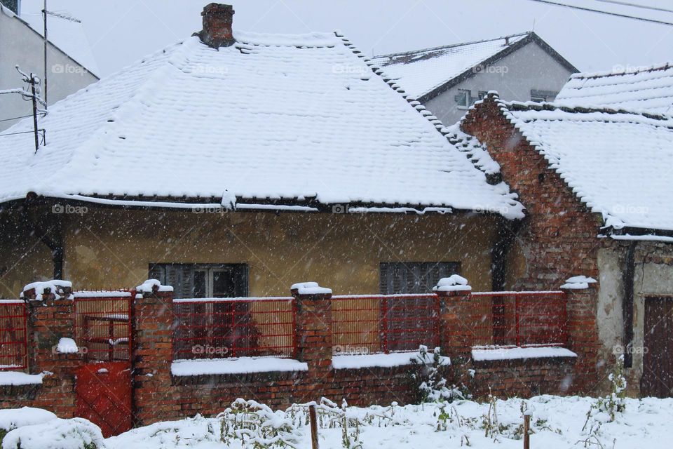 Winter landscape in the countryside.  Snow is falling on roofs, fences, and the street