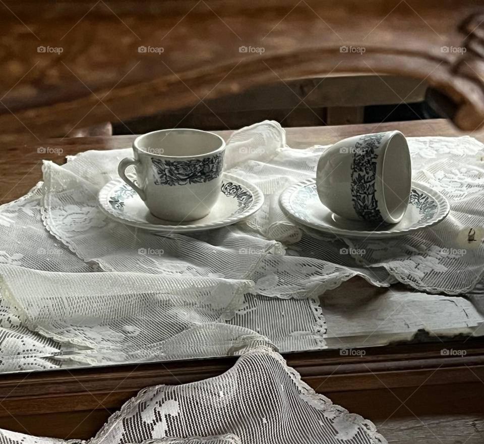 Two vintage patterned porcelain cups with saucers standing on a table covered with a fine cloth.