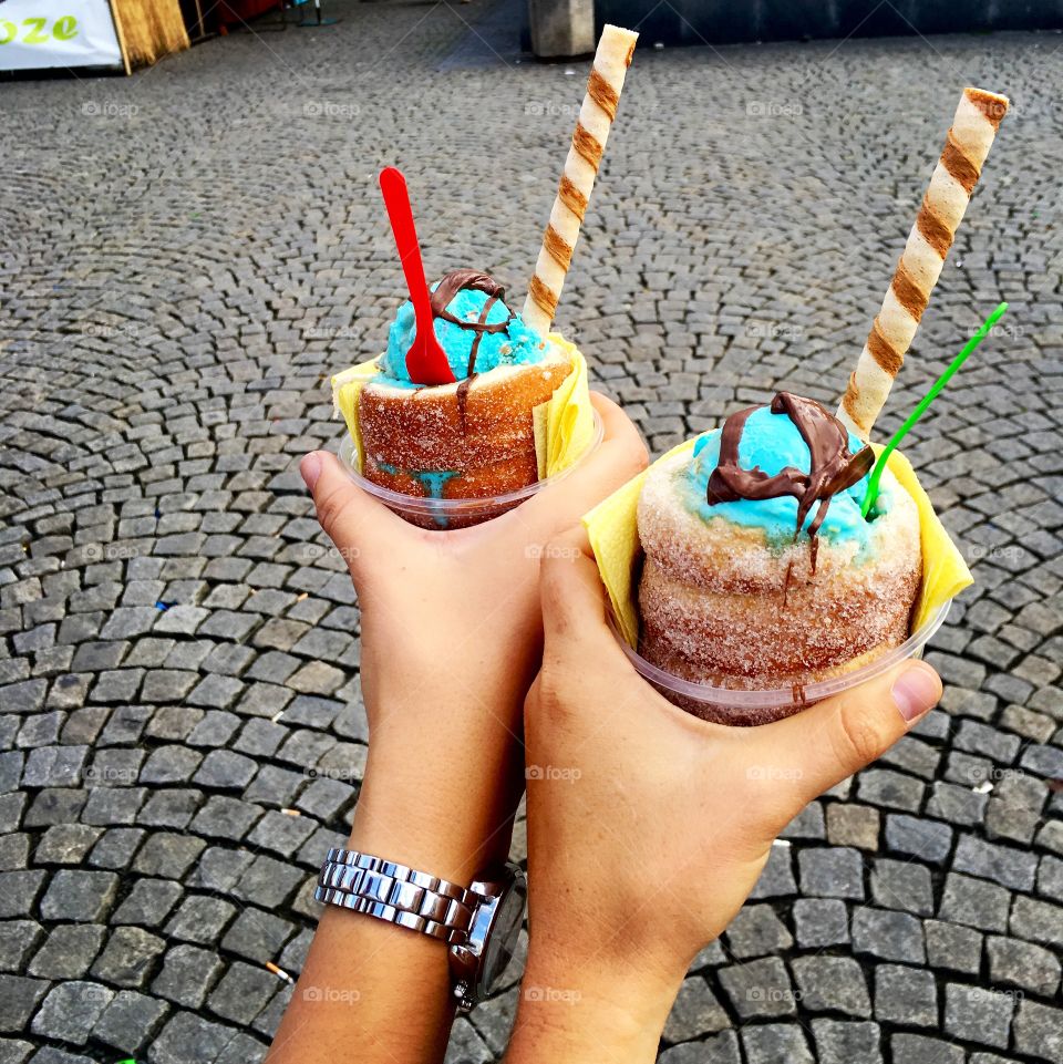 Two people holding dessert outdoors