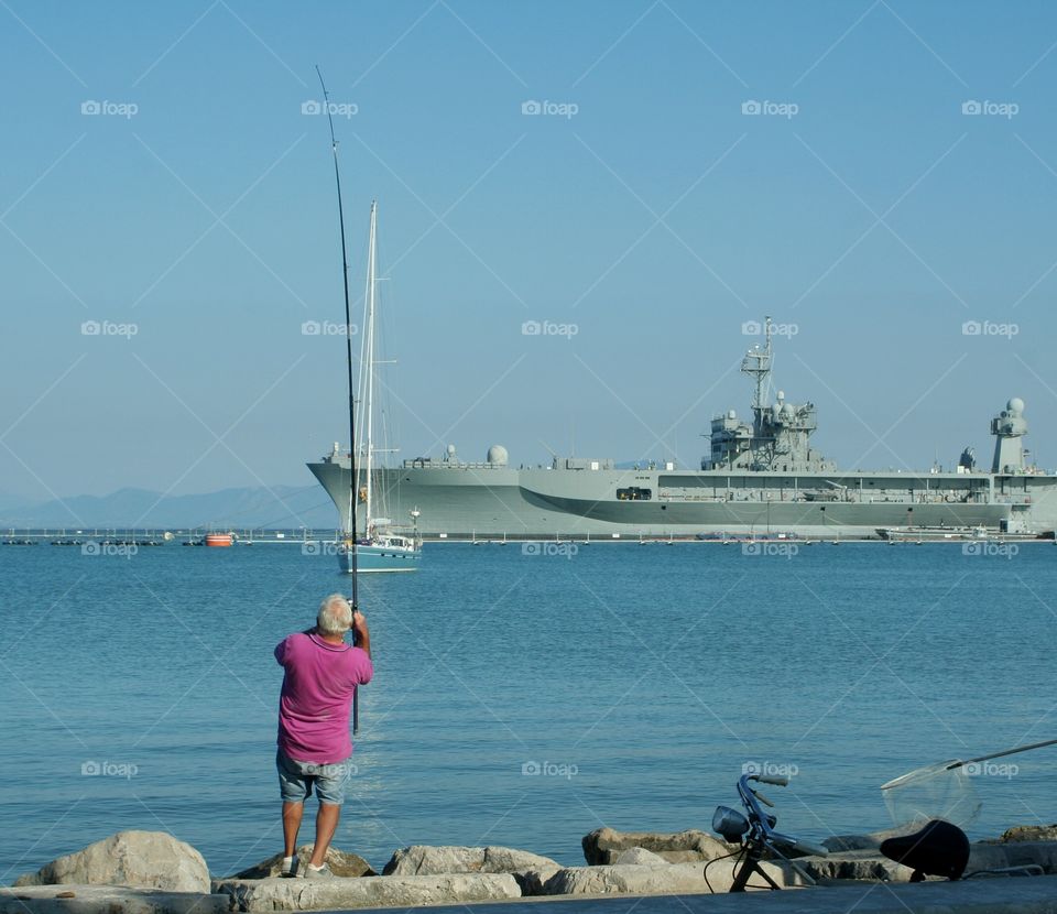 Fishing with a military fregade on background