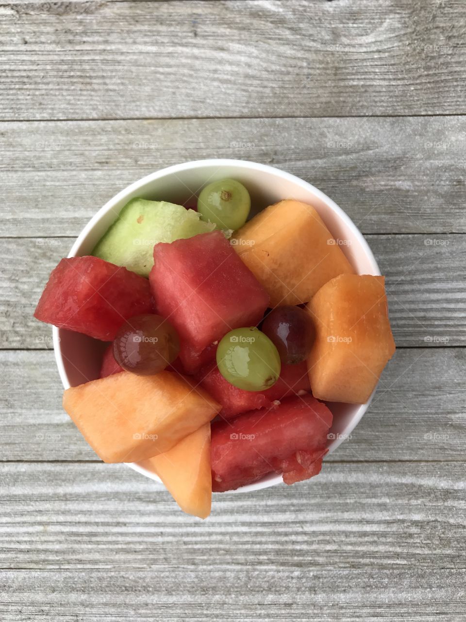 A small white bowl with a variety of summertime fruit for lunch!