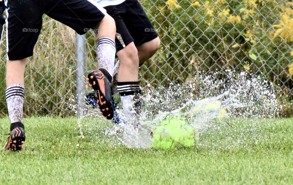 Soccer players in the rain. Water splashing