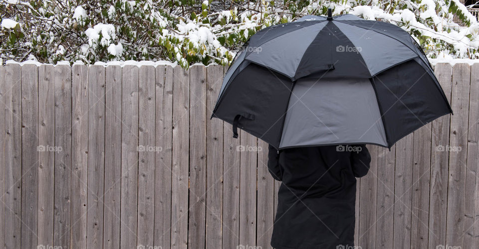 Back view of a woman holding an umbrella in the snow