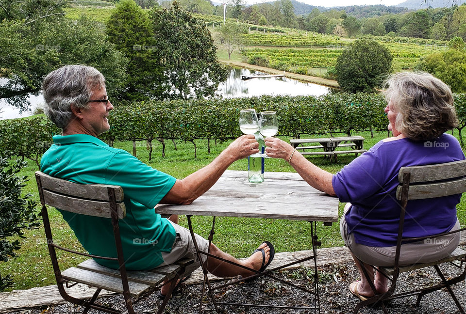 Happy couple drinking wine in a vineyard.