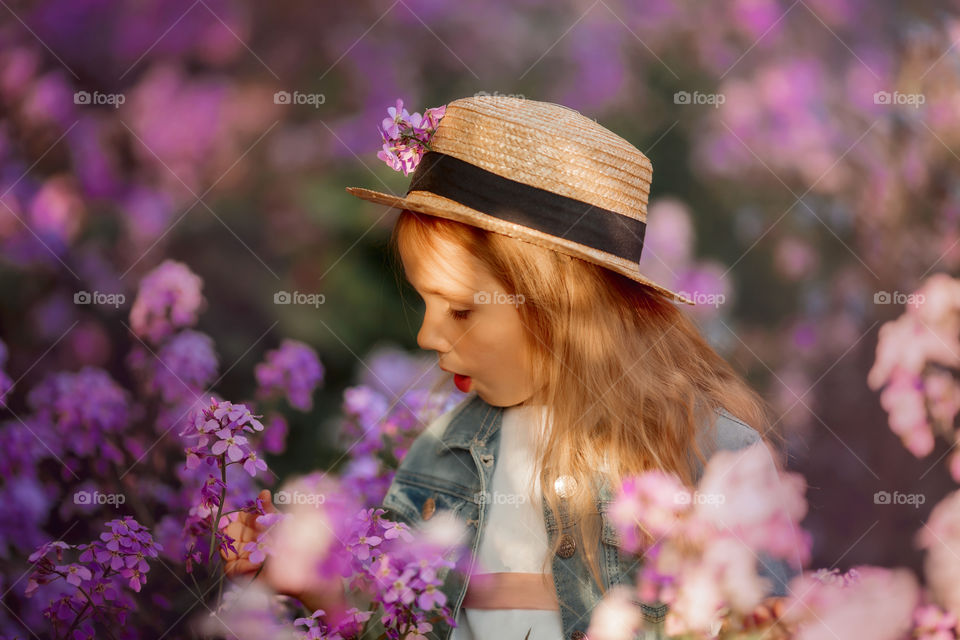 Cute little girl portrait in blossom meadow at sunset 