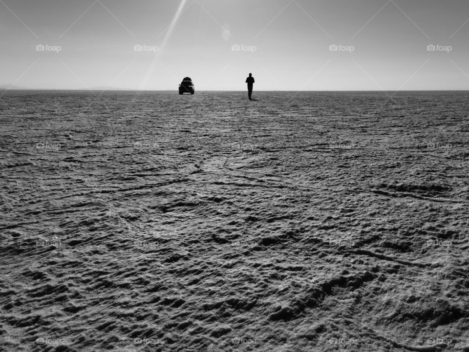 Solitary man and his car on a vast salt flat