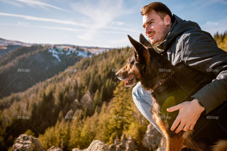 Man on a hike with his dog admiring the view over a cliff