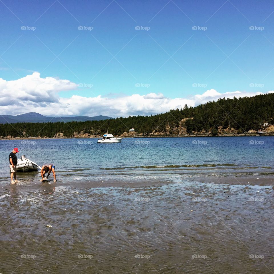 Father and son tying their dingy to the shore in Buccaneer Bay, on Thormanby Island, British Columbia, Canada 