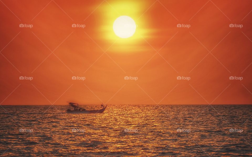 sunset by the beach with fishing boat coming home