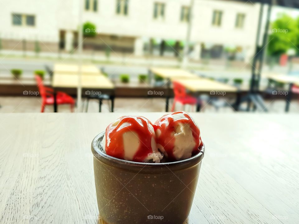 Cup with ice cream on the table at blurred street background.