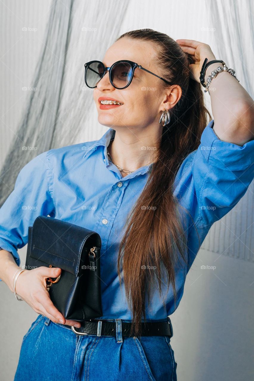Young millennial generation woman wearing stylish trendy accessories silver and gold jewelry: rings, earrings, bracelets, bag, necklace, sunglasses