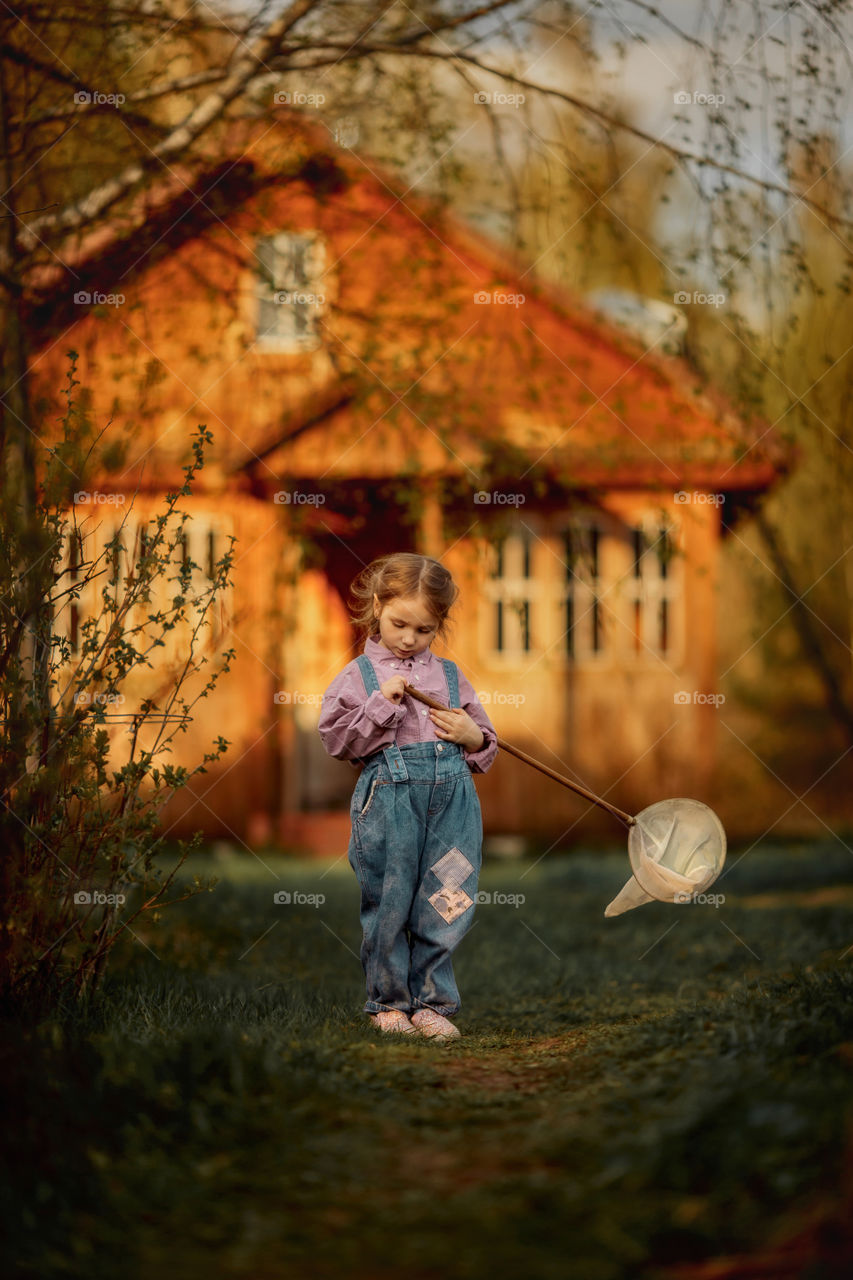 Little girl with butterfly net outdoor at sunset