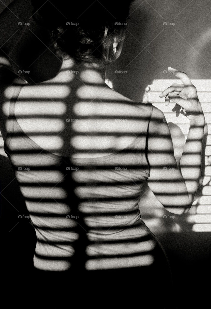 Shadow from blinds on woman’s back