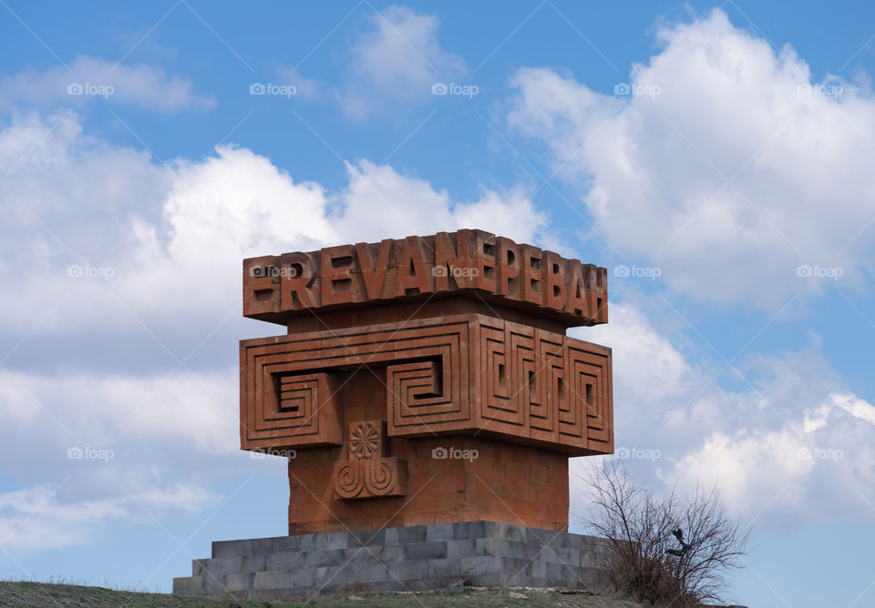 Yerevan, Armenia - April 3, 2017: Gigantic red stone sign / sculpture welcoming visitors to Yerevan by side of the M4 road to the north towards Sevan region on parly cloudy early April day.