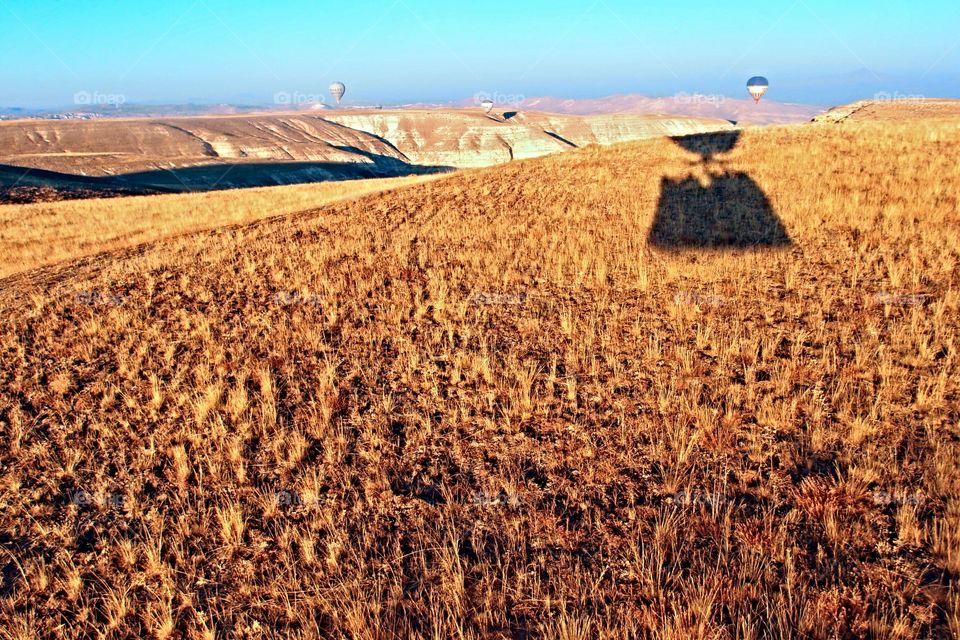 flying shadow. shadow of hot air balloon basket..a contrast to the golden color of the grass