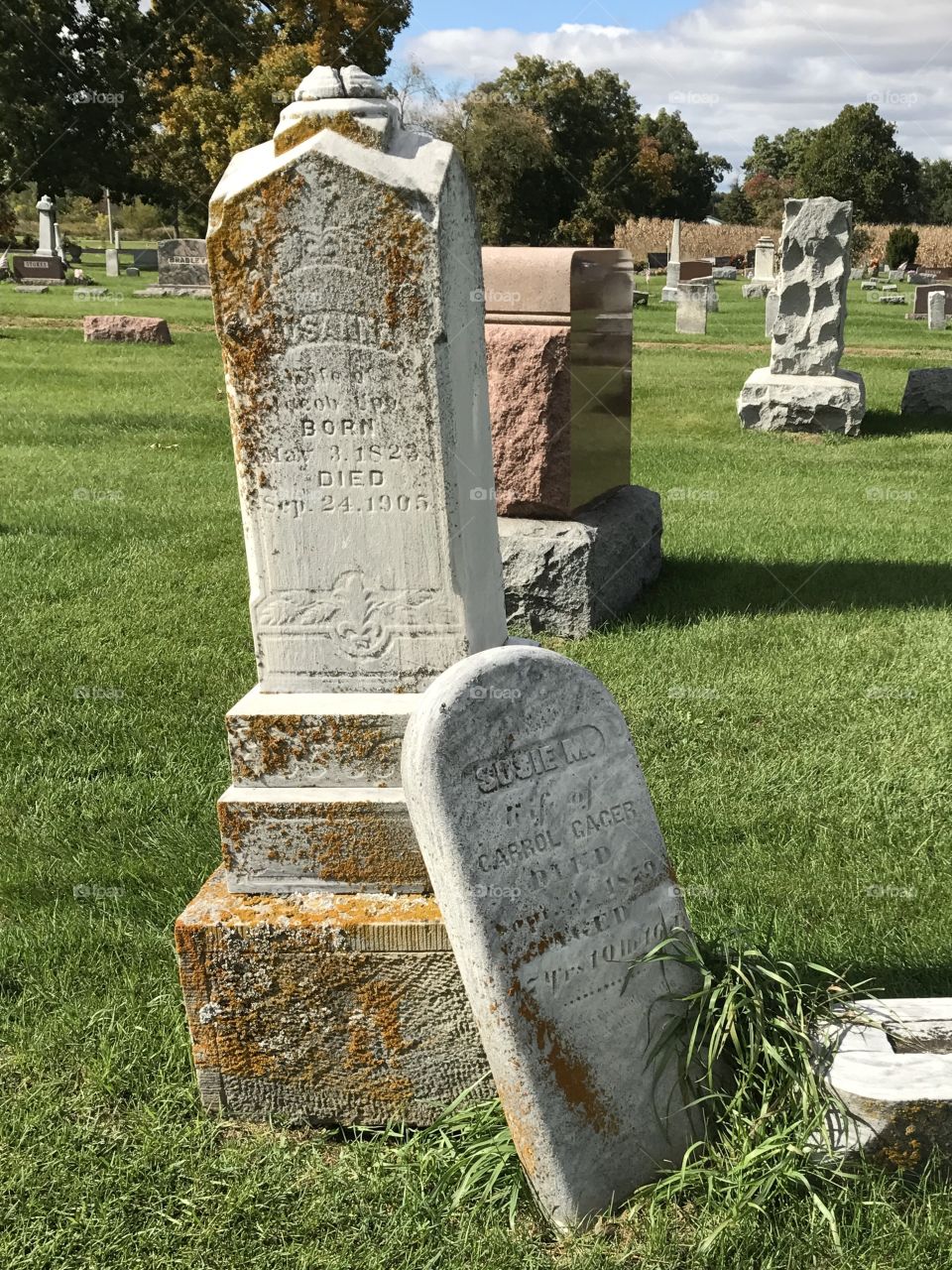 A monument with a broken headstone leaning against it