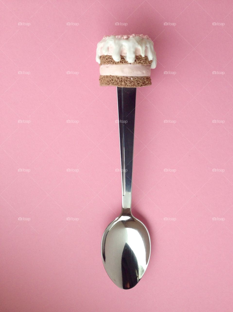 Spoon with cupcake on top on pink background 