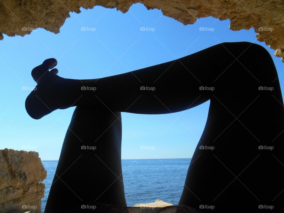 beautiful seascape, female legs barefoot relaxing, cave view, summer training