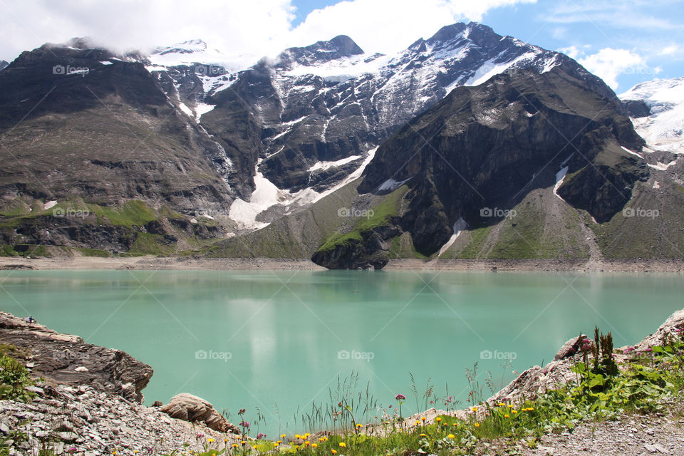 Hiking trail in the mountains, view of lake and mountain peaks with snow 