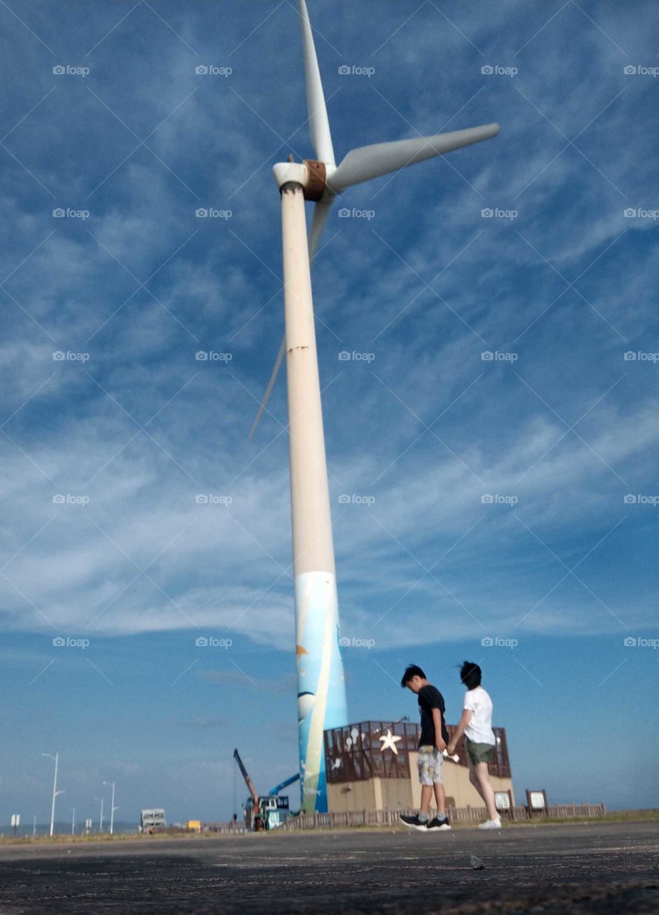The art of composition: POV. seaside windmills provide us clean energy, mother and child tooke a trip for relaxing and watching seaside landscape. blue sky and sea were very beautiful.