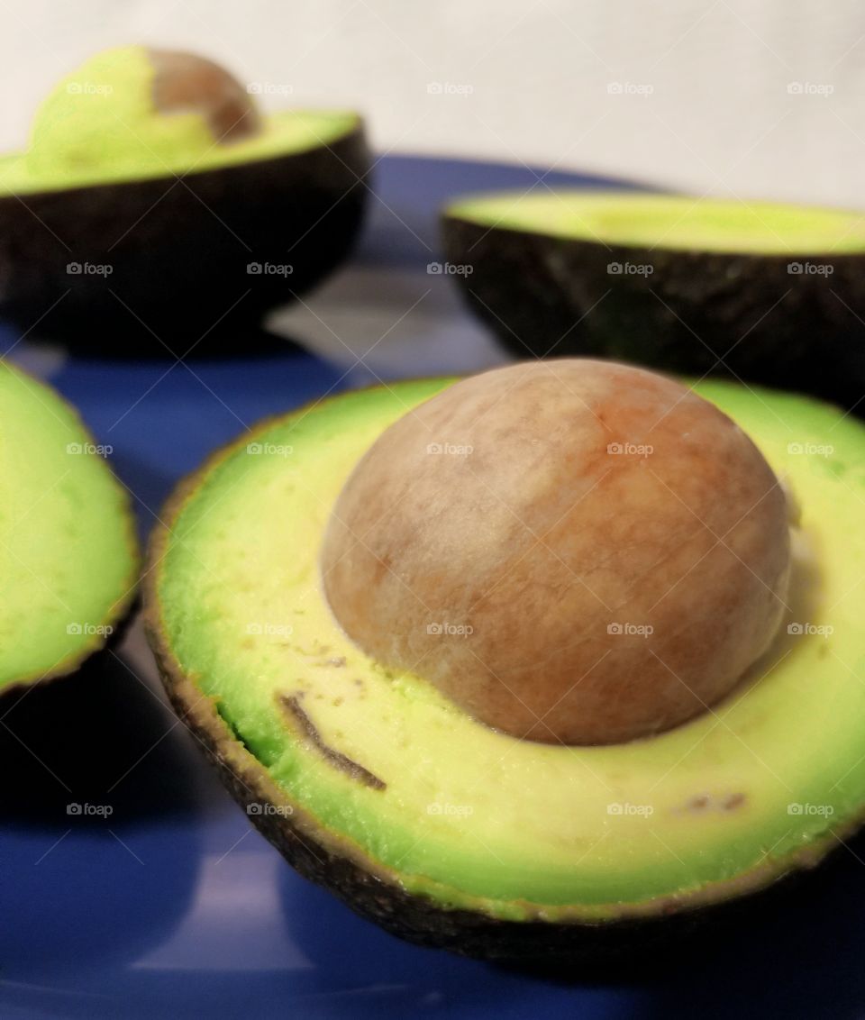 A macro shot of ripe avocados presented on a blue plate.