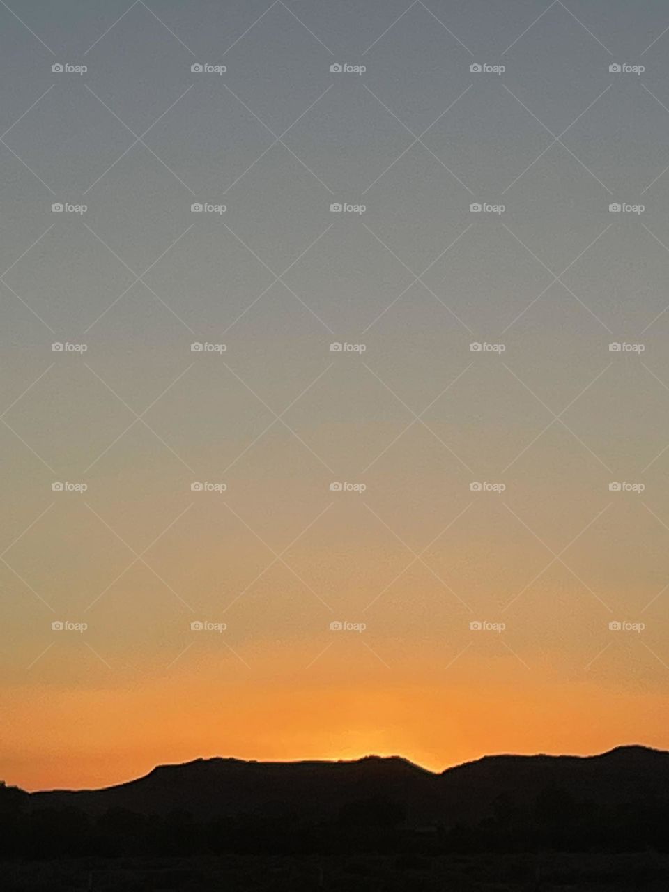 A orange sunset with mountains below.