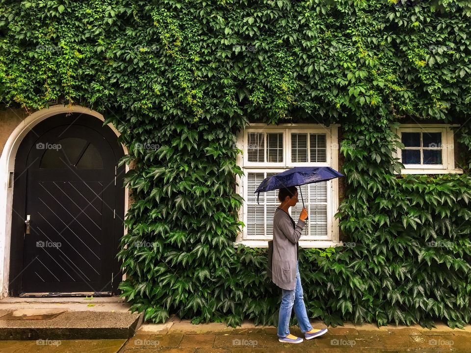 Woman walking near house decorated with green vine