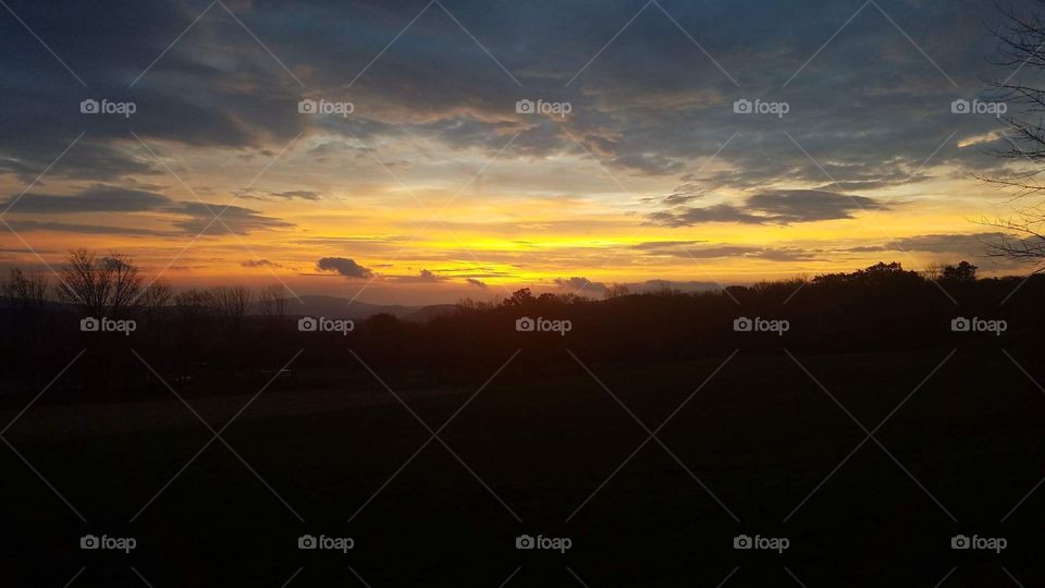 Rolling hill sunrise with stunning beautiful clouds. Peach, yellow, orange, lavender 