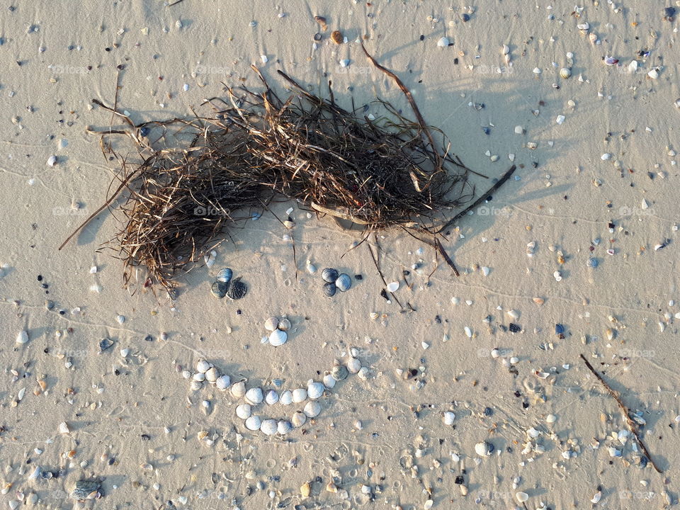 Smiling face on the sand from the shells