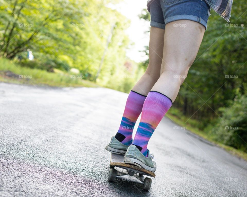 Skateboarding a damp road while the sun breaks through 