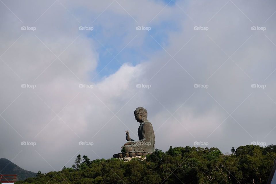 The Tian Tan Buddha atop Wisdom Peak, Lantau Island (Hong Kong). A monument to peace and enlightenment, perched serene, west-facing to the backdrop of blue skies and rolling white clouds.