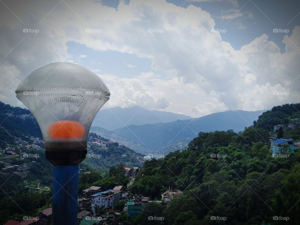 light post. street lights. lamp post. light pole.  photo captured at the daytime. Blue sky and clouds also got trapped. Civilized area, house and buildings at the mountain range. Ancient place.